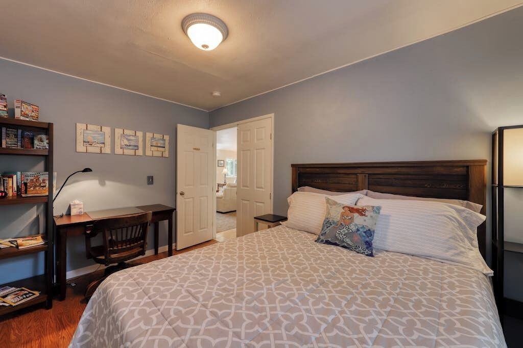 A bedroom with a bed, a desk, a chair, and a bookshelf.