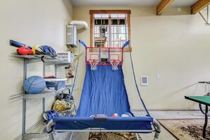 Ein Heimfitnessraum mit Basketballkorb, Trainingsgeräten und einem Fenster.