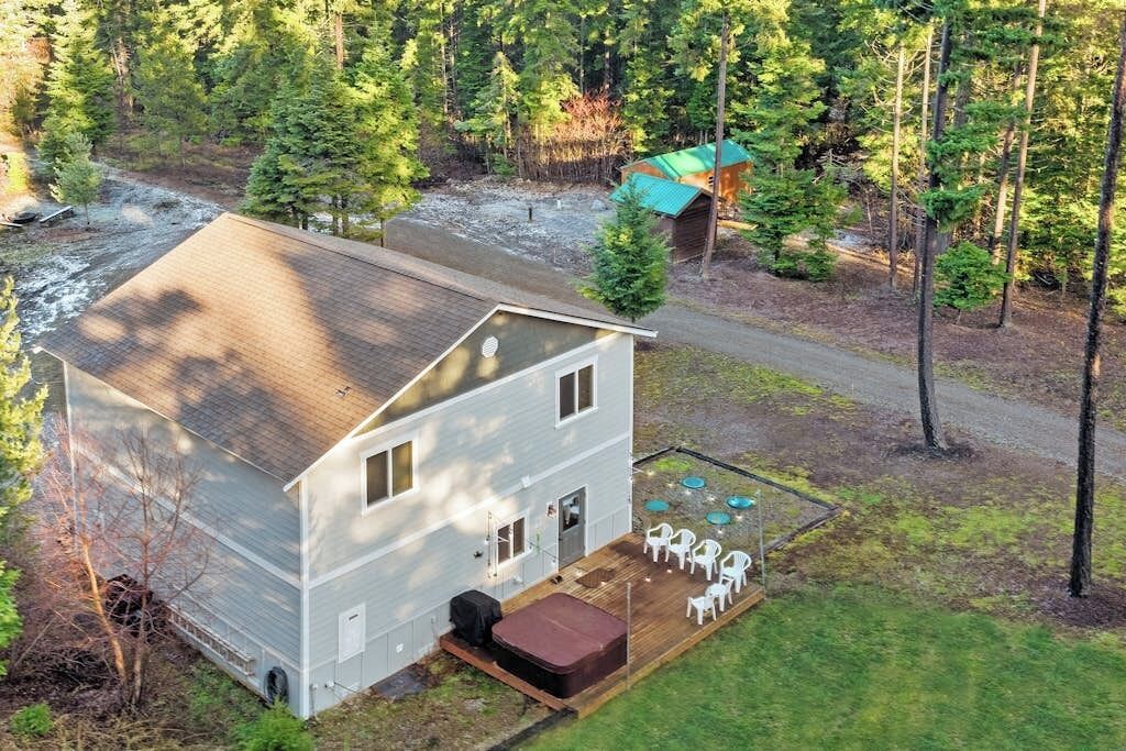 Une maison à deux étages dotée d’une terrasse et d’un espace extérieur aménagé pour s’asseoir.
