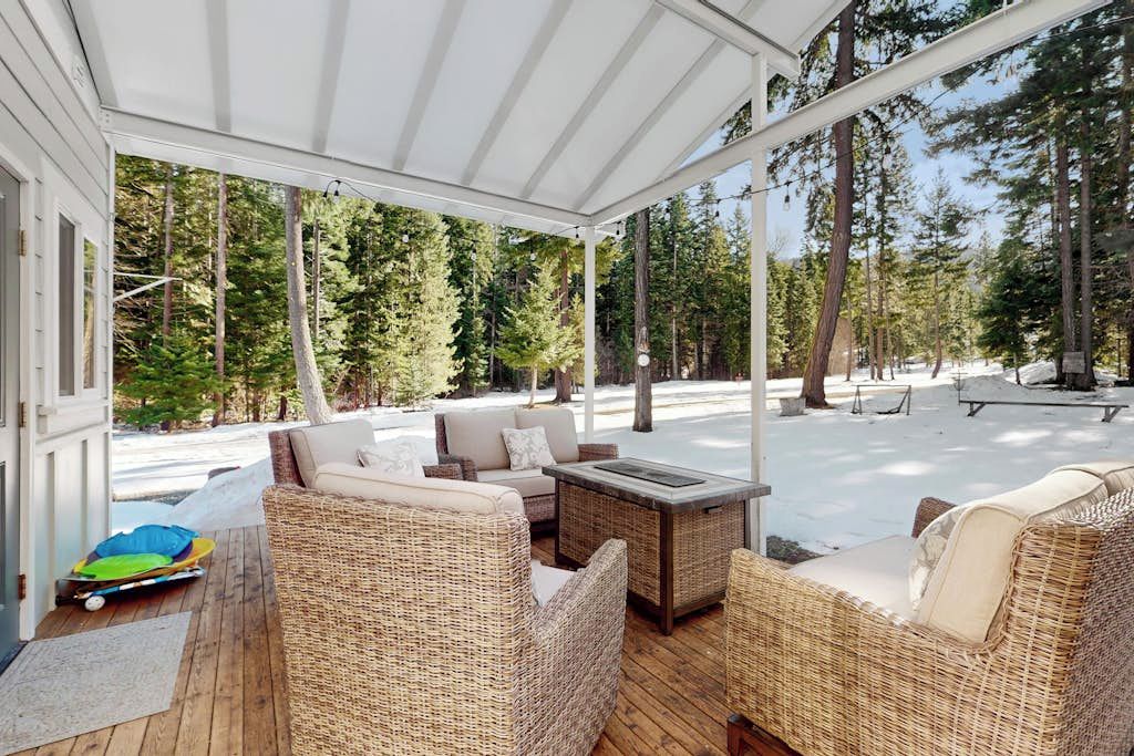 A covered outdoor seating area with wicker furniture and a fire pit.