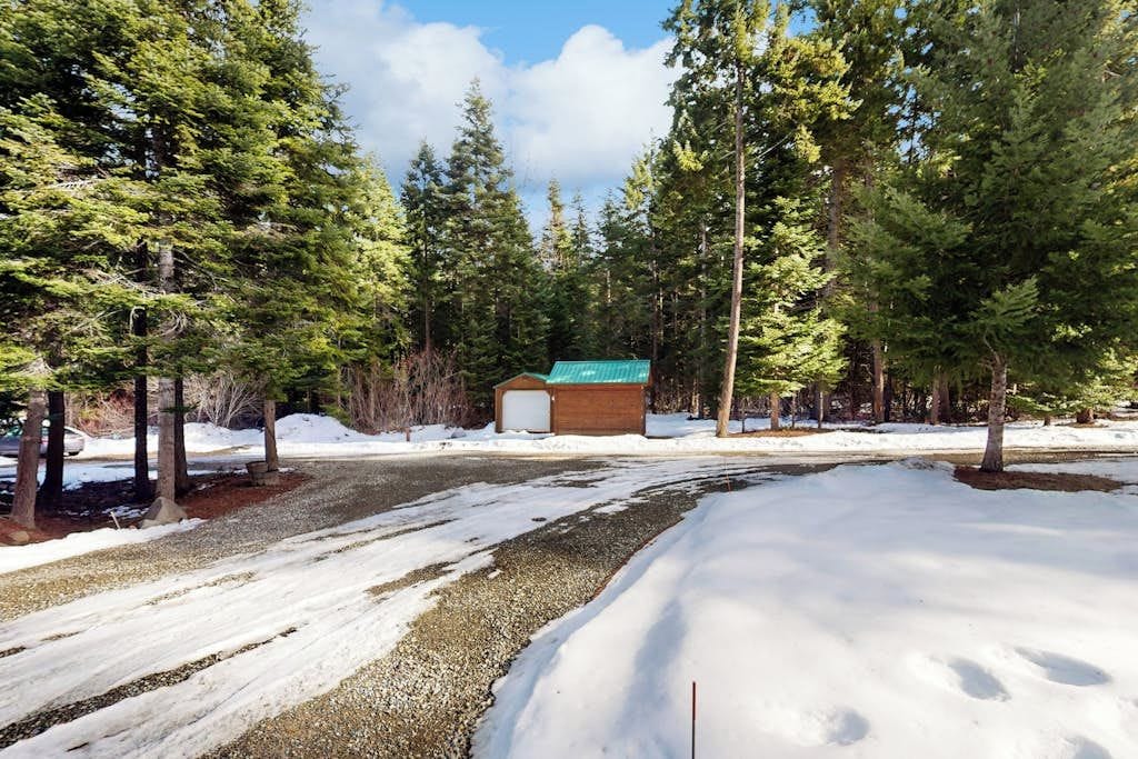 A cabin surrounded by a forest with snow on the ground.