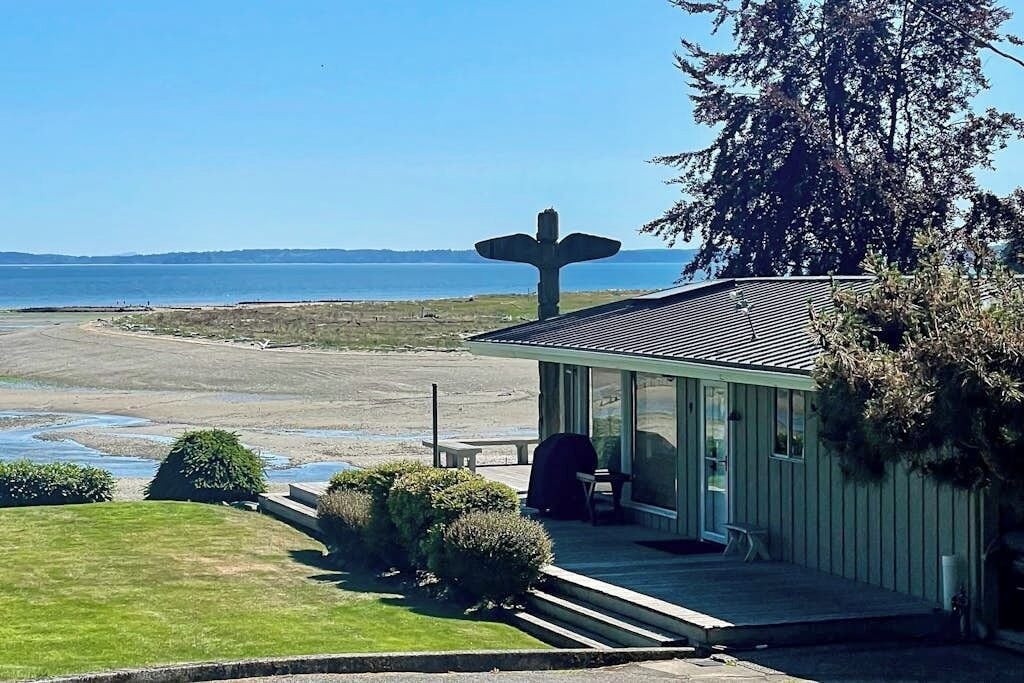 A coastal building with a large bird sculpture, a patio, and a view of the sea.