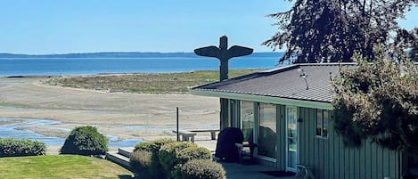 Un edificio costero con una gran escultura de ave, un patio y vistas al mar.