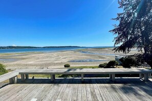 Terraza de madera con vista a una playa y cielo despejado.