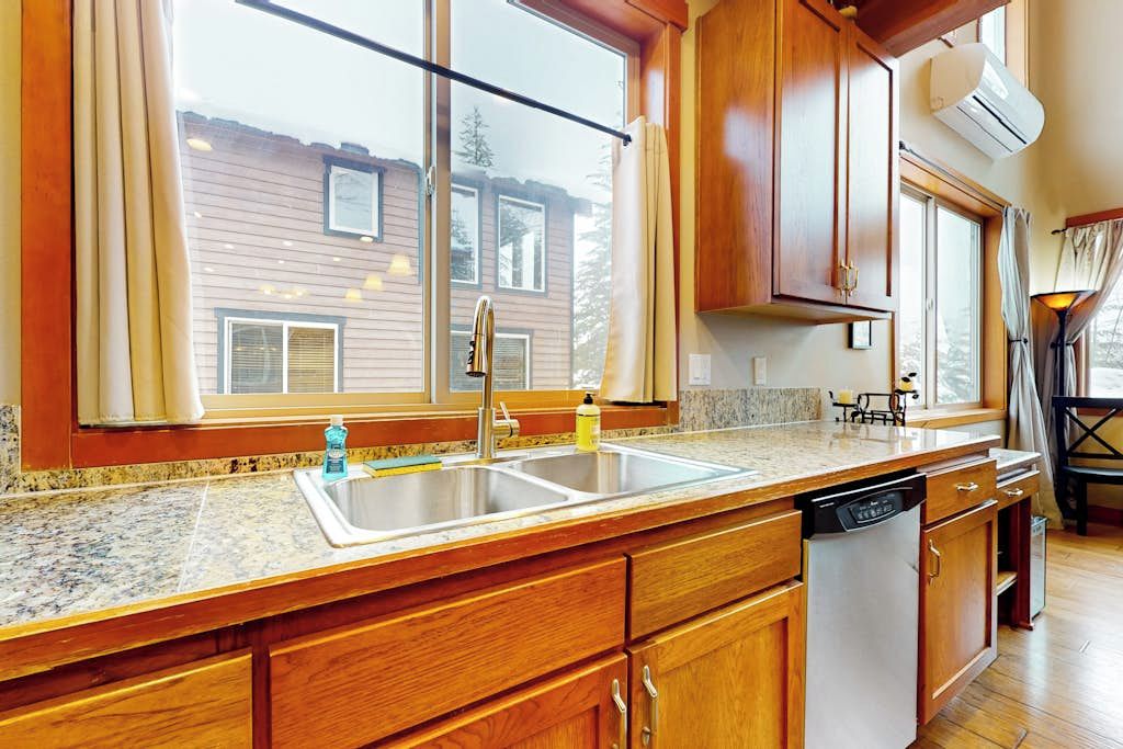 A kitchen with wooden cabinets, a granite countertop, a sink, and a dishwasher.