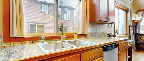 A kitchen with wooden cabinets, a granite countertop, a sink, and a dishwasher.