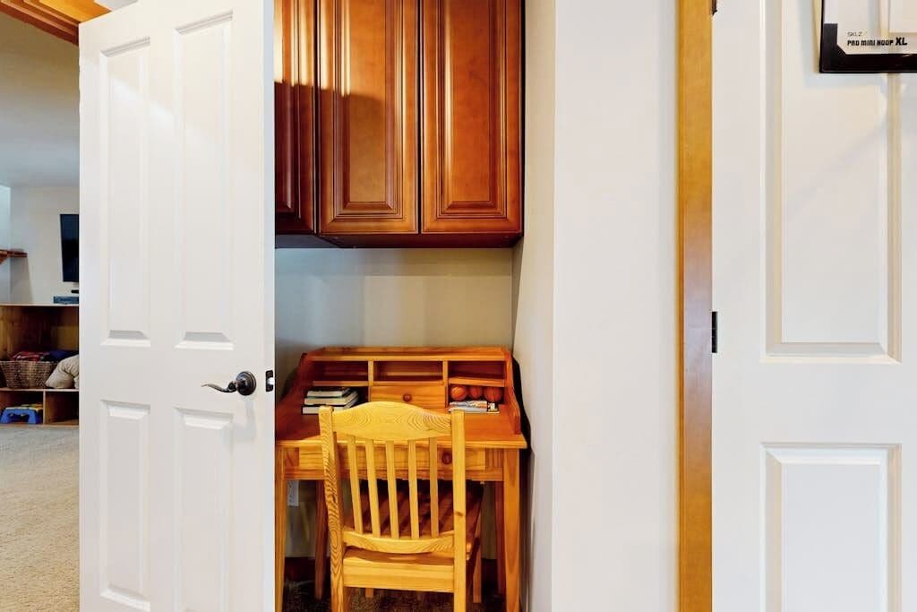A room with a wooden desk, chair, and cabinets.