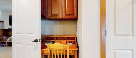 A room with a wooden desk, chair, and cabinets.