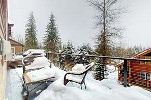 Ein mit Schnee bedeckter Balkon mit einem Stuhl und einer Holzterrasse.