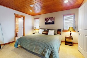 Ein Schlafzimmer mit einem großen Bett, Holzboden, zwei Nachttischen mit Lampen, einer Tür und einem Bild an der Wand.