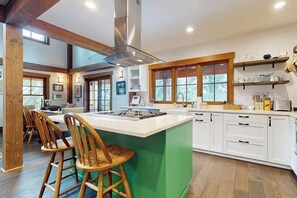 A spacious kitchen with a central island, wooden chairs, and a large window. - 3BR ski In and Out access, indoor sauna, & fireplace (Snoqualmie Pass)
