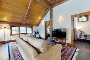A living room with a large sofa, a flat-screen TV, and a wooden ceiling. - 3BR ski In and Out access, indoor sauna, & fireplace (Snoqualmie Pass)