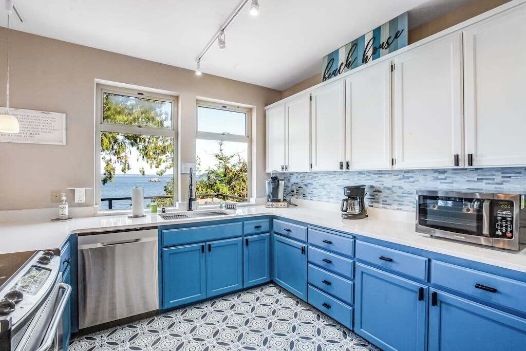 Una cocina moderna con armarios azules, una estufa de acero inoxidable y un microondas.