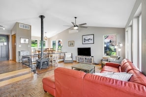 A spacious living room with a fireplace, a television, and a large window offering a view of the outdoors. - Impeccable 3BR Oceanview Dog Friendly - Hot Tub (Port Ludlow)