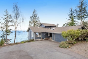 A two-story house with a garage, a driveway, and a view of the water. - Impeccable 3BR Oceanview Dog Friendly - Hot Tub (Port Ludlow)