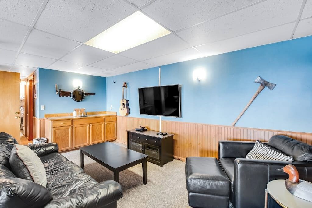 Una sala de estar con pared azul, muebles de madera, un televisor, una guitarra y una chimenea.