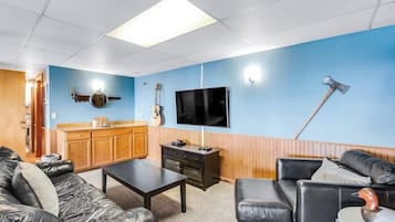 Una sala de estar con pared azul, muebles de madera, un televisor, una guitarra y una chimenea.