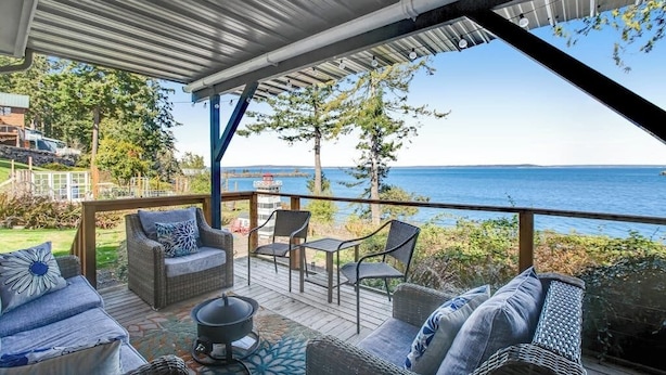 An outdoor deck with wicker furniture and a view of the sea.