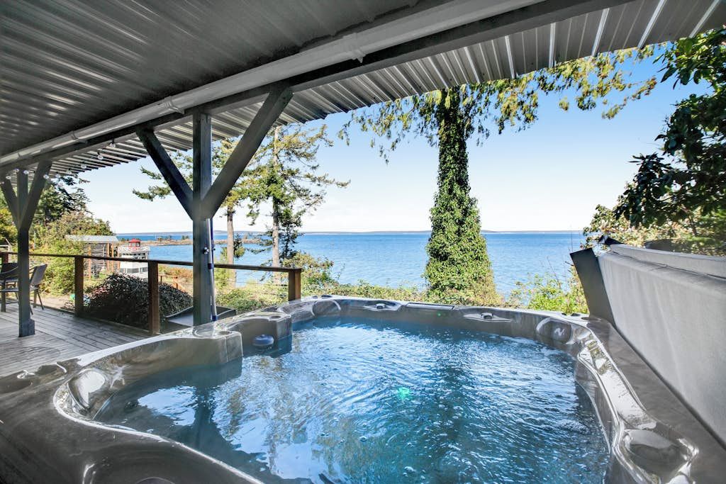 Un jacuzzi bajo una zona techada con vista al mar.