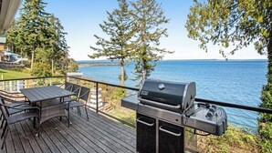 A deck with a grill and table, overlooking a body of water and trees. - Impeccable 3BR Oceanview Dog Friendly | Hot Tub (Port Ludlow)