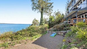 A coastal property with a gravel path leading to a deck, overlooking a body of water.