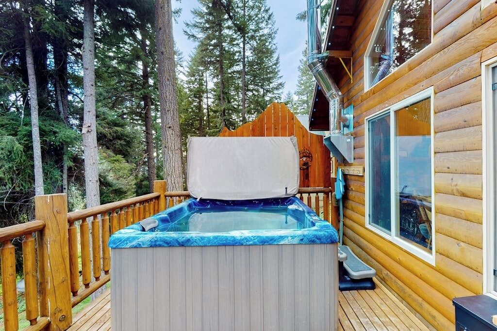 A hot tub on a wooden deck with a view of a forest.