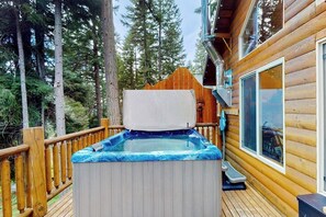Ein Whirlpool auf einer Holzterrasse mit Blick auf einen Wald.