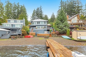 A waterfront property with multiple buildings, a dock, and a small boat. - 1BR lakefront guest house with kayaks & game table (Olympia)