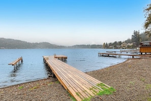 Eine Holzstege ragt in ruhiges Wasser hinein, über ihm strahlend blauer Himmel.
