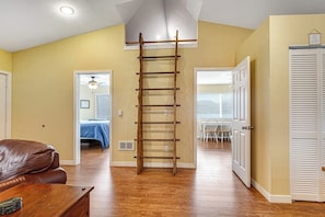A room with a wooden ladder, a brown leather couch, and a wooden table. - 1BR lakefront guest house with kayaks & game table (Olympia)