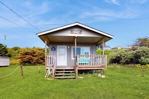 Un edifici petit d'una sola planta amb un porxo i un rètol que diu 'Driftwood Cottage'.