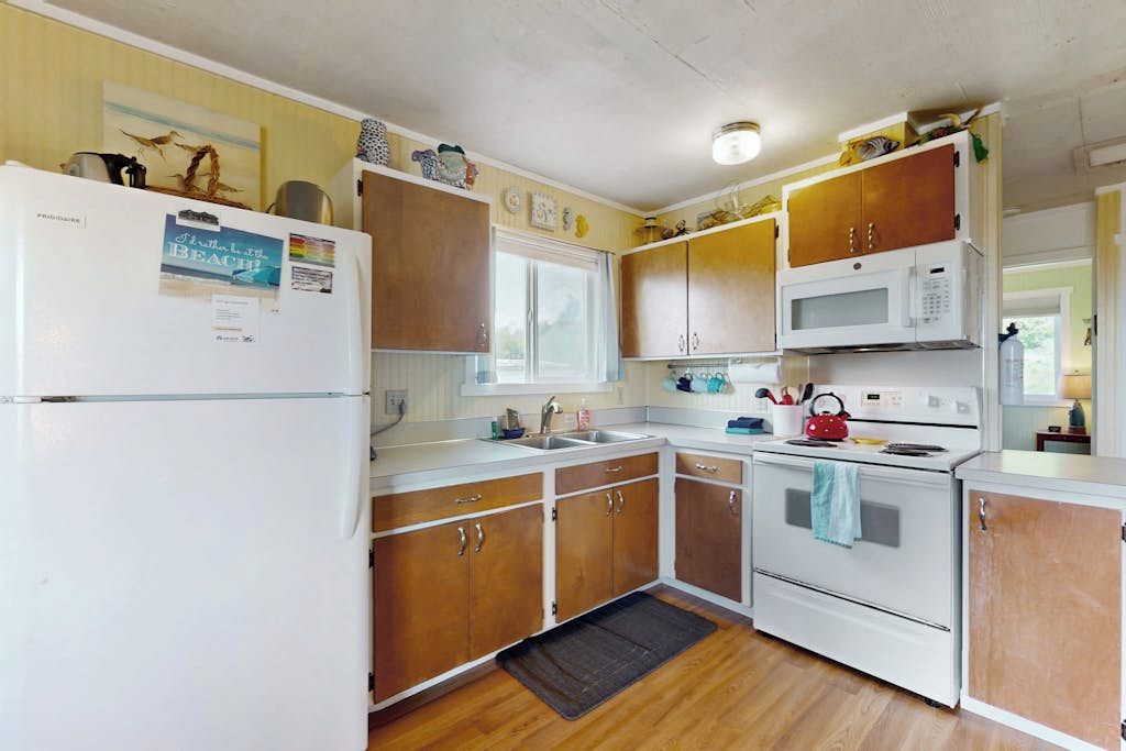 A kitchen with wooden cabinets, a white refrigerator, a microwave, and an oven.