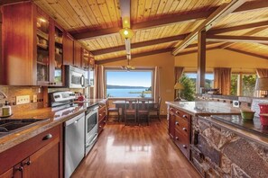 A kitchen with wooden cabinets, a central island, and a view of the outdoors. - Gorgeous 2BR Soundview - Balcony - Washer Dryer (Lilliwaup)