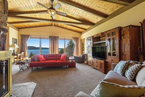 A spacious living room with a large sofa, a television, and wooden cabinets. - Gorgeous 2BR Soundview - Balcony - Washer Dryer (Lilliwaup)