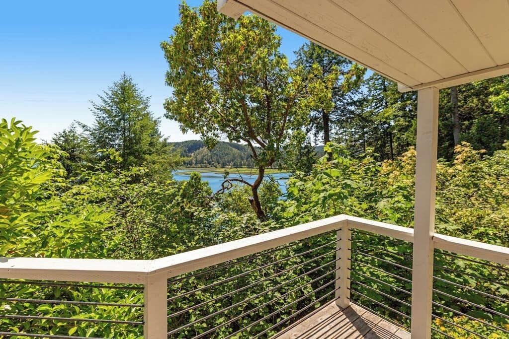 A balcony with a view of a lake and forest.