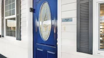 A blue door with a decorative glass panel, a small sign above it, and a window with shutters to the left.