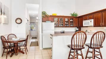 A kitchen with wooden cabinets, a microwave, and a dining area with a table and chairs.