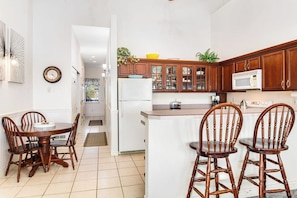 A kitchen with wooden cabinets, a microwave, and a dining area with a table and chairs. - 1BR Oceanfront - Deck - Sauna - Fireplace (Ocean Shores)