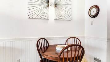 Un comedor con una mesa redonda de madera y cuatro sillas, un reloj en la pared y un adorno mural.