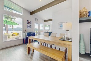 A modern kitchen with a wooden table, bench, and a view of the outdoors through large windows. - Modern Waterfront Home with Amazing Views (Port Orchard)