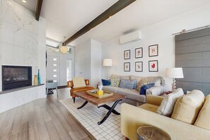 A modern living room with a fireplace, a sofa set, a coffee table, and a TV. - Modern Waterfront Home with Amazing Views (Port Orchard)