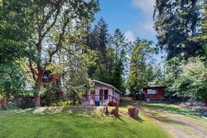 A two-story house with a porch, surrounded by trees and a grassy yard.