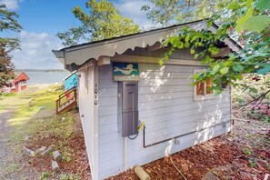 A small cabin with a sign reading 'Mermaid Cove Lodge' and a view of a lake.