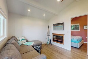 A living room with a sofa, a fireplace, and a painting on the wall. - Waterfront couples getaway with patio (Allyn)