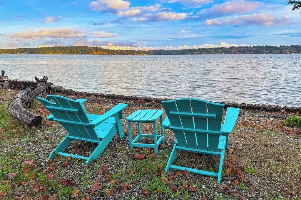 Une vue sur le lac, avec deux fauteuils Adirondack turquoise et une petite table.