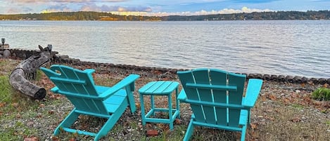 Une vue sur le lac, avec deux fauteuils Adirondack turquoise et une petite table.