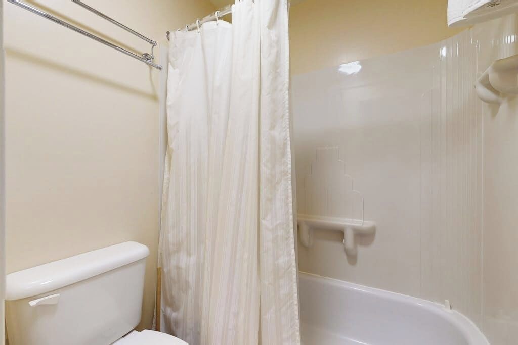 Un baño con inodoro, ducha con cortina y bañera.