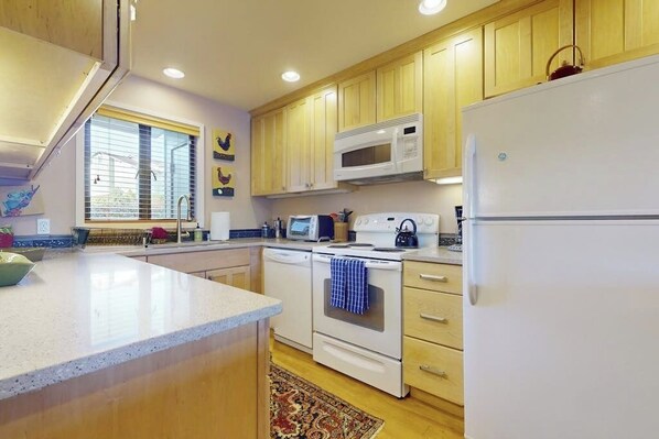 A kitchen with wooden cabinets, a microwave, a stove, and a refrigerator.