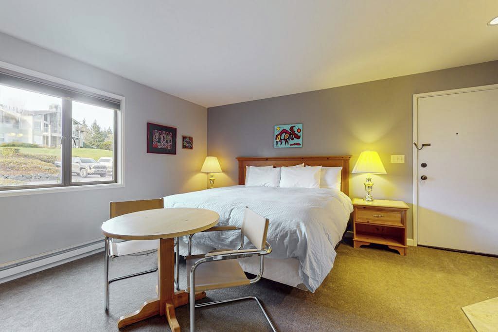 Une chambre d’hôtel avec un lit, des tables de chevet, une table ronde et des chaises.