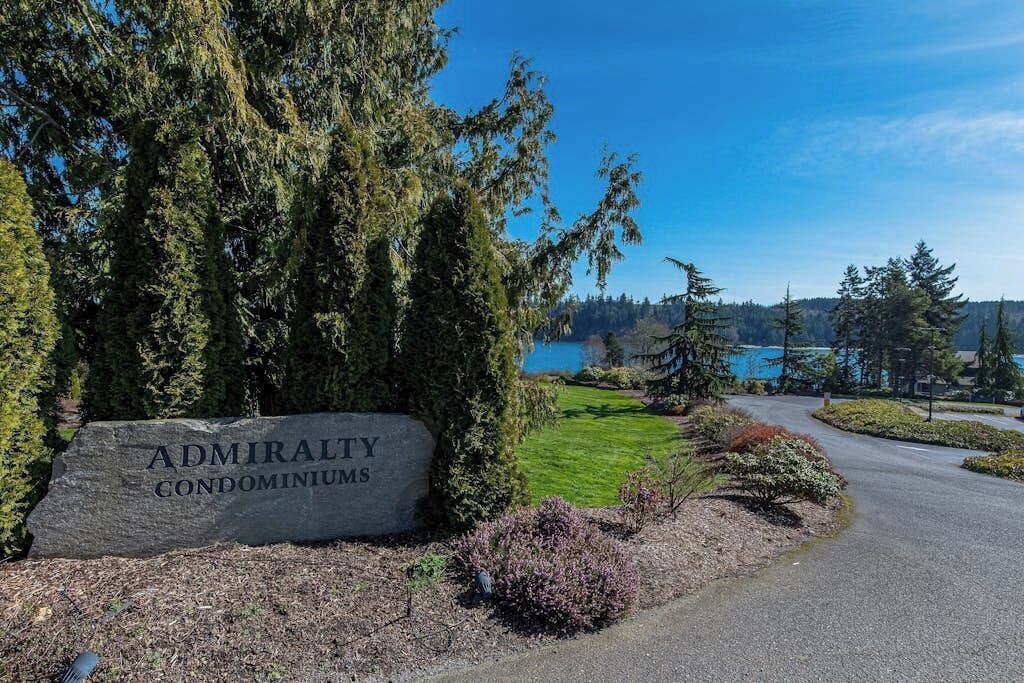 Une enseigne indiquant l’emplacement des condominiums Admiralty, avec vue sur un lac et des arbres.
